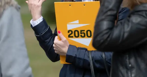 Kobieta prezentuje żółtą teczkę z napisem "2050", symbolizującą strategię polską 2050 na wybory samorządowe i europejskie.