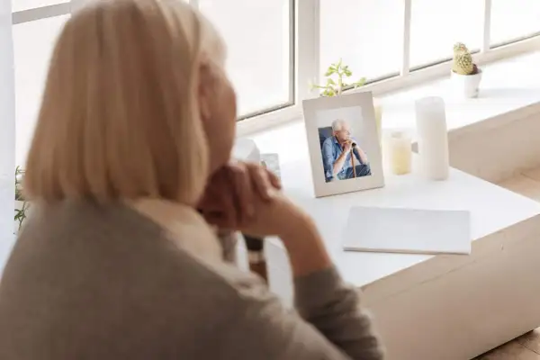 Kobieta patrzy na zdjęcie zmarłego męża. Czy renta wdowia komu dokładnie przysługuje z projektu lewicy?