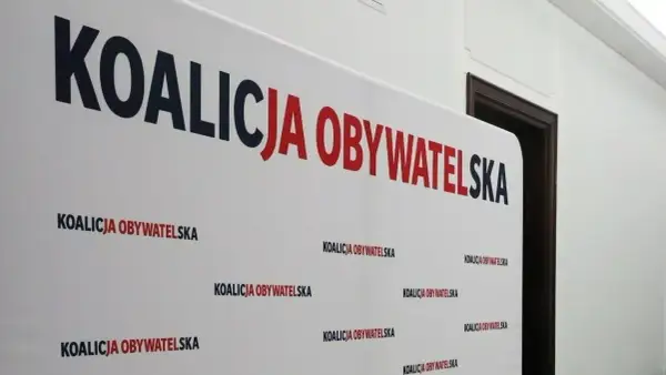 Białe tło z napisem "KOALICJA OBYWATELSKA" w dużych, czerwono-granatowych literach. Pod spodem powtarza się mniejszy napis. To symboliczne tło dla dyskusji o stosunku Koalicji Obywatelskiej do Europejskiego Zielonego Ładu.
