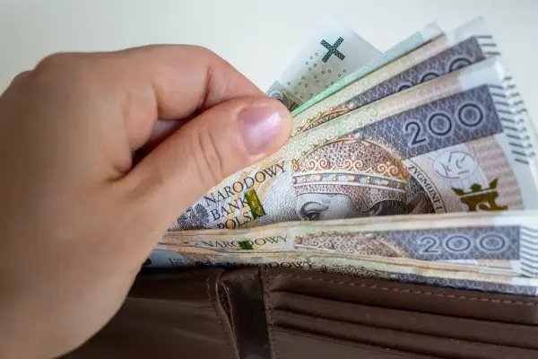 Dłoń wsuwa banknoty 200 zł do portfela. To symbol obietnic Koalicji Obywatelskiej dotyczących składki zdrowotnej dla przedsiębiorców.