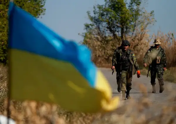 Ukraińska flaga na pierwszym planie, za nią dwaj żołnierze idący drogą. Hasło "stop ukrainizacji Polski" budziło kontrowersje, a Konfederacja używała go w swojej retoryce.