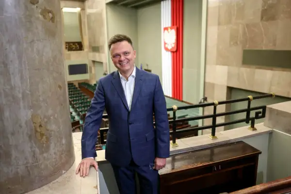 Szymon Hołownia jako Marszałek Sejmu: ocena jego kadencji i potencjalne wpadki. Uśmiechnięty polityk w garniturze na tle sali sejmowej.