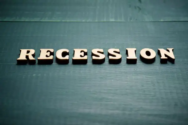 Drewniane litery układają słowo "RECESSION". To pojęcie ekonomiczne, które opisuje spowolnienie gospodarcze.