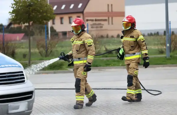 Strażacy w akcji, jeden z węża wodnego. Zastanawiasz się, ile zarabia strażak? To praca pełna poświęcenia.