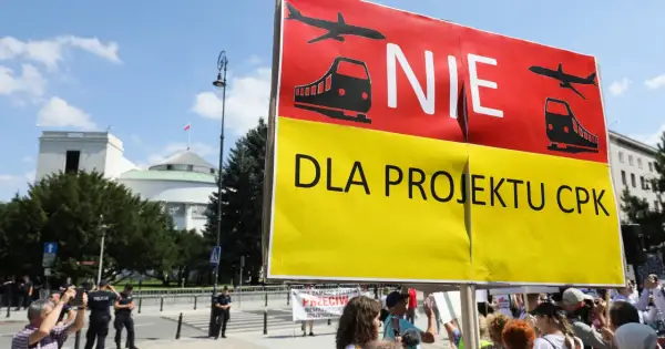 Protestujący sprzeciwiają się projektowi CPK. Transparent "NIE DLA PROJEKTU CPK" z symbolami samolotu i pociągu.