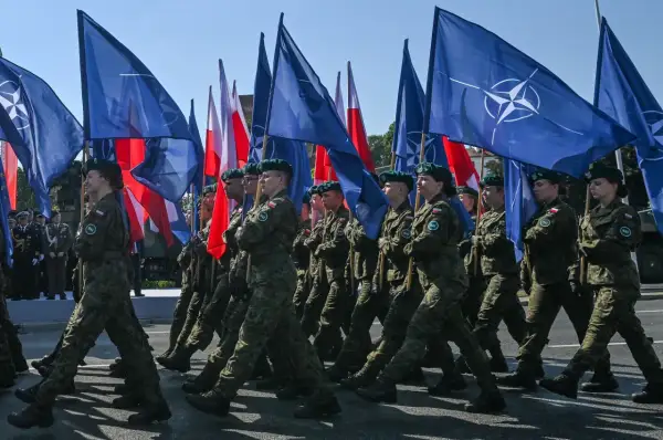 Żołnierze maszerują z flagami NATO i Polski. To obraz polityki obronnej koalicji obywatelskiej, która stawia na zakupy sprzętu wojskowego.