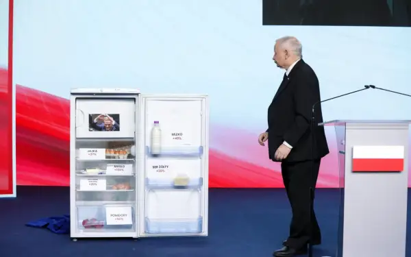 Otwarta lodówka z produktami i etykietami wzrostu cen, obok polityk. Ilustracja programu gospodarczego PiS a realia inflacji.